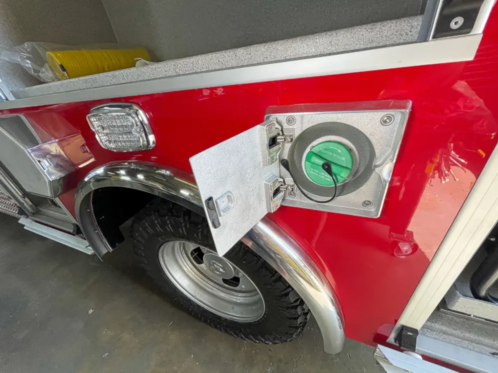 Exterior view of small fire truck showing cab, body compartments, and wheel/tire area.